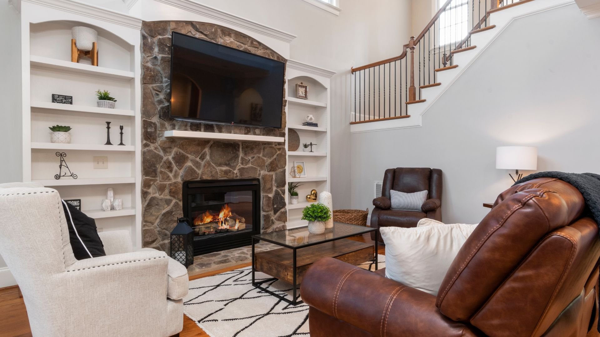 Cozy living room with stone fireplace, leather furniture, and built-in shelves