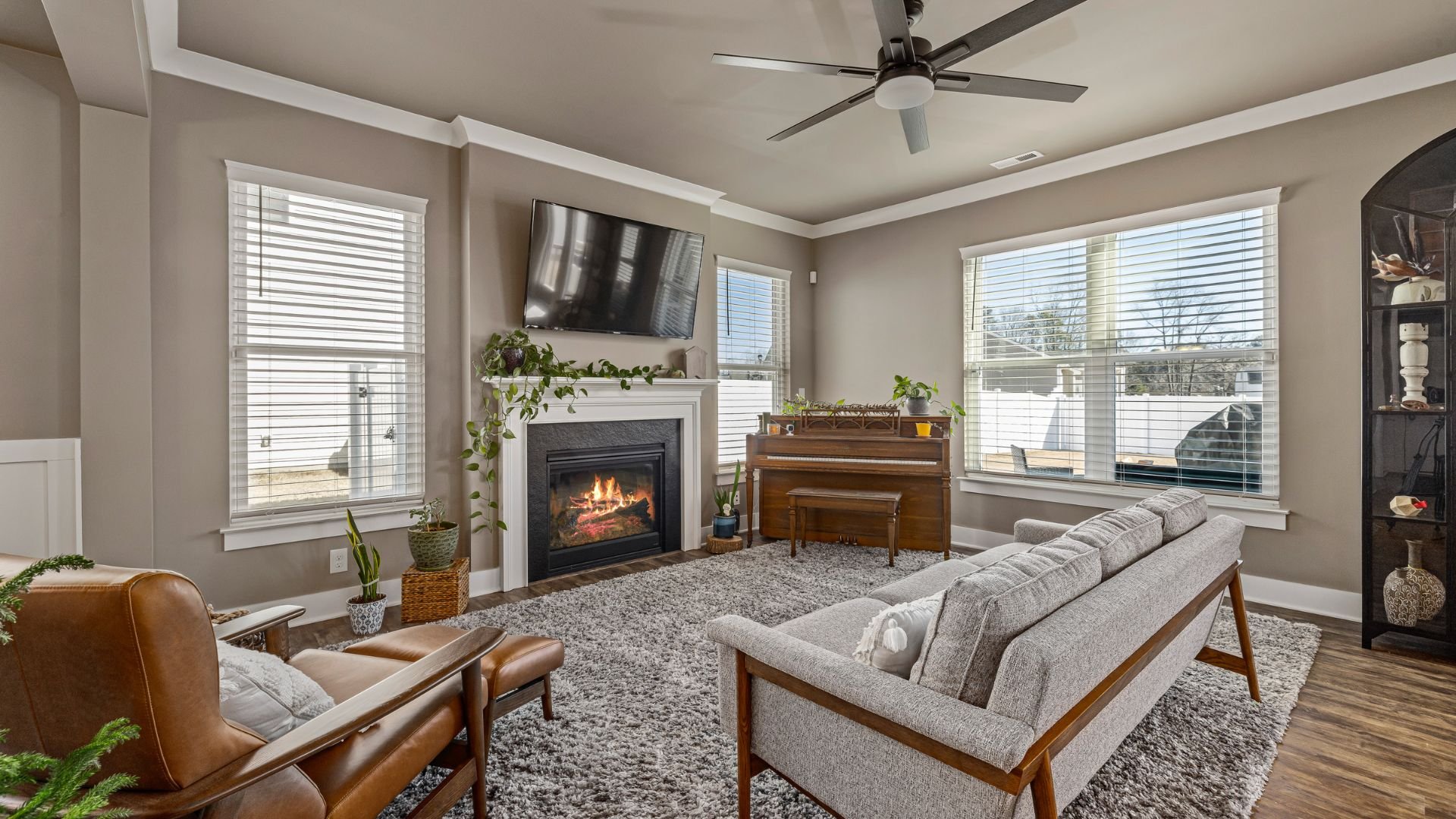 Cozy living room with fireplace, plants, piano, and modern furniture
