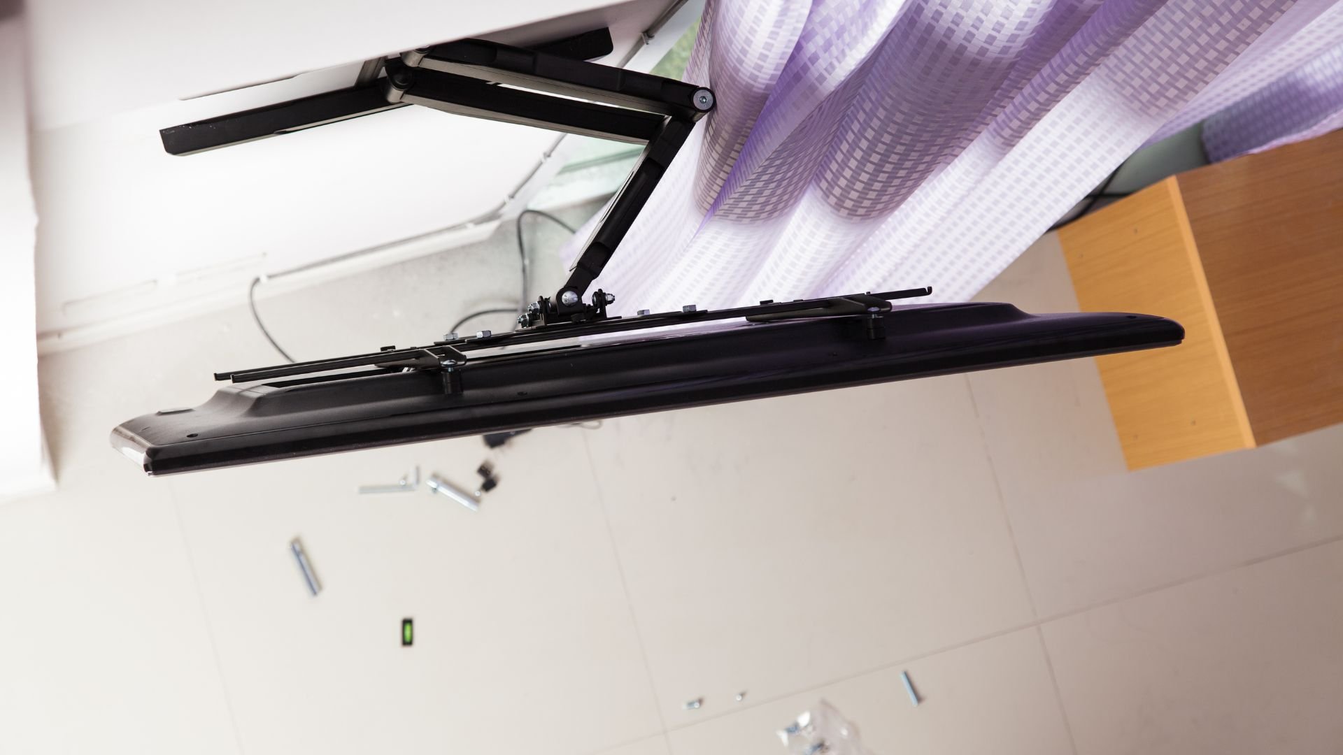 Black wall-mounted adjustable monitor arm with cables and level