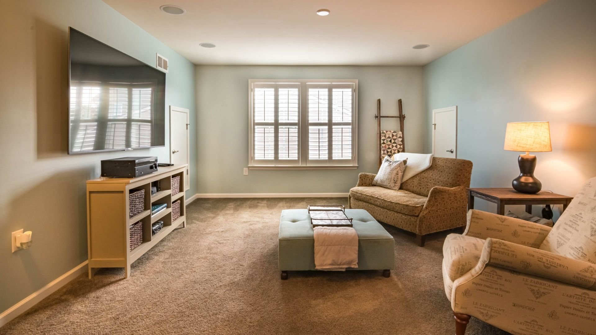 Cozy living room with brown carpet, neutral furniture, and large windows