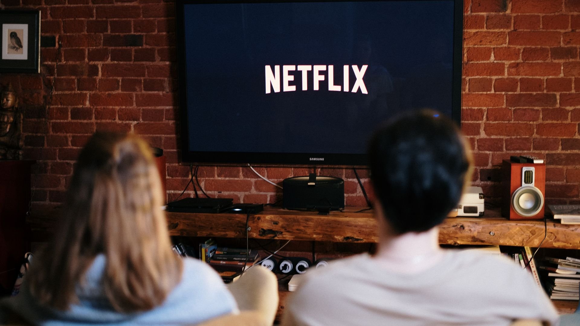 Two people watching Netflix on a Samsung TV against a brick wall