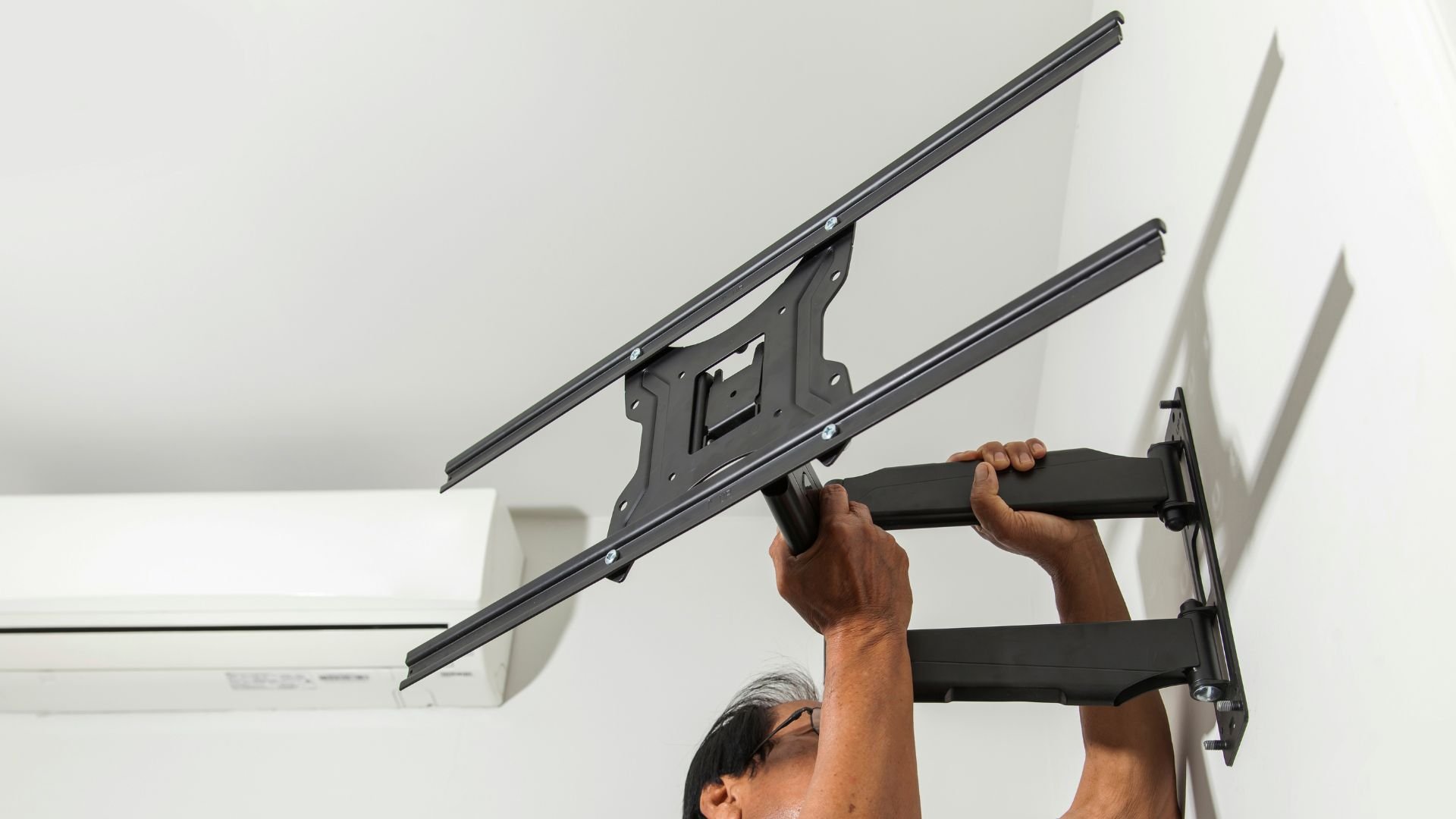 Person installing articulating wall mount for TV or monitor