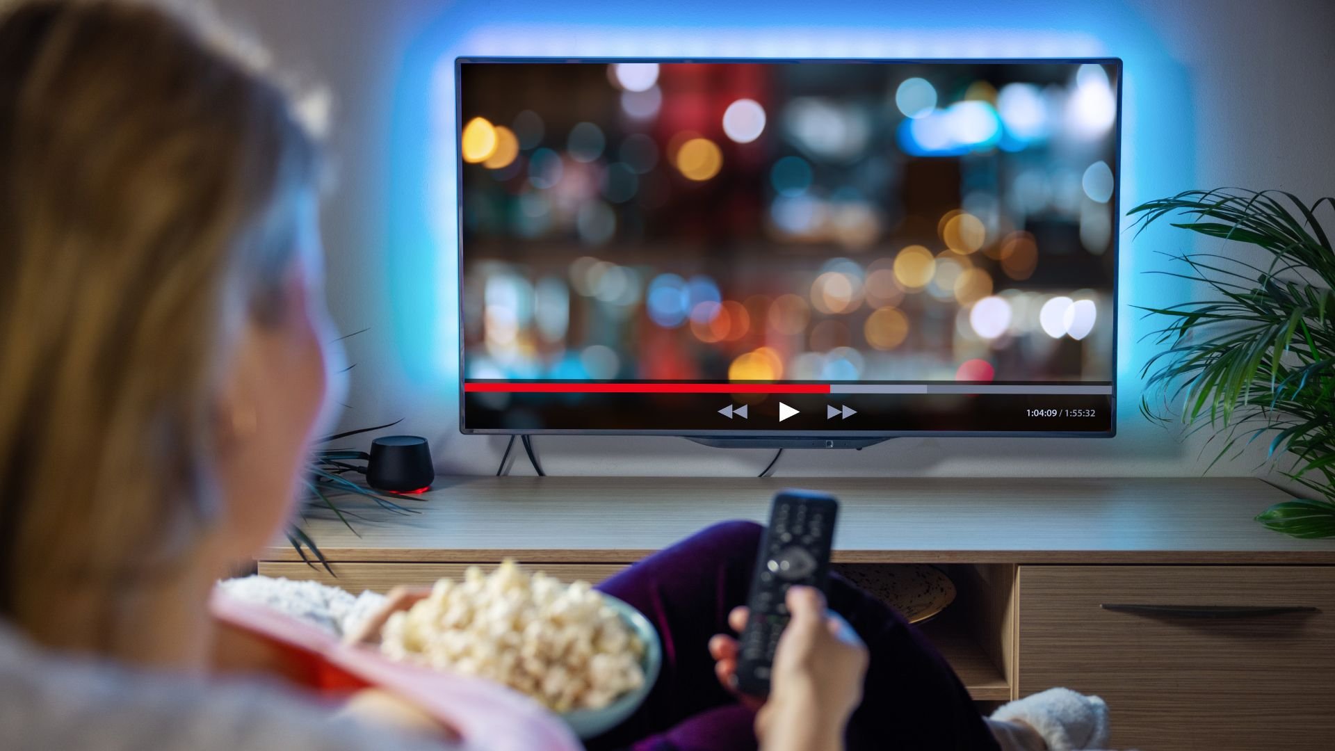 Person watching blurry movie with popcorn and remote control