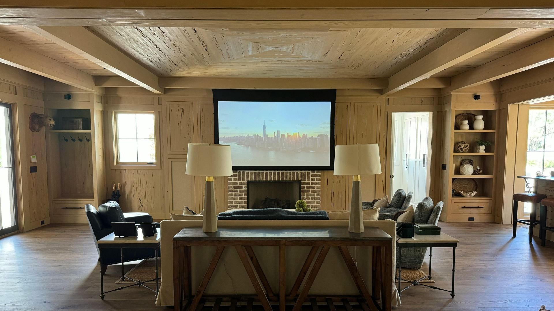 Cozy wood-paneled living room with city skyline projection over fireplace