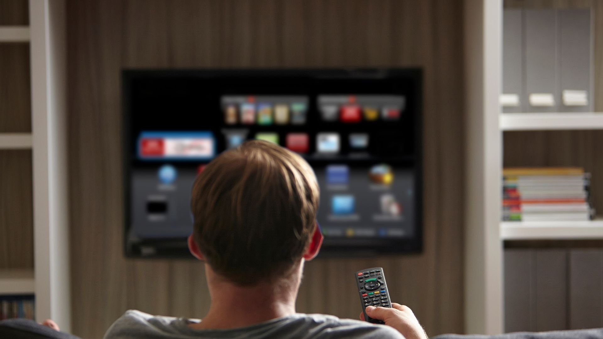 Person watching TV with remote control, browsing streaming service menu