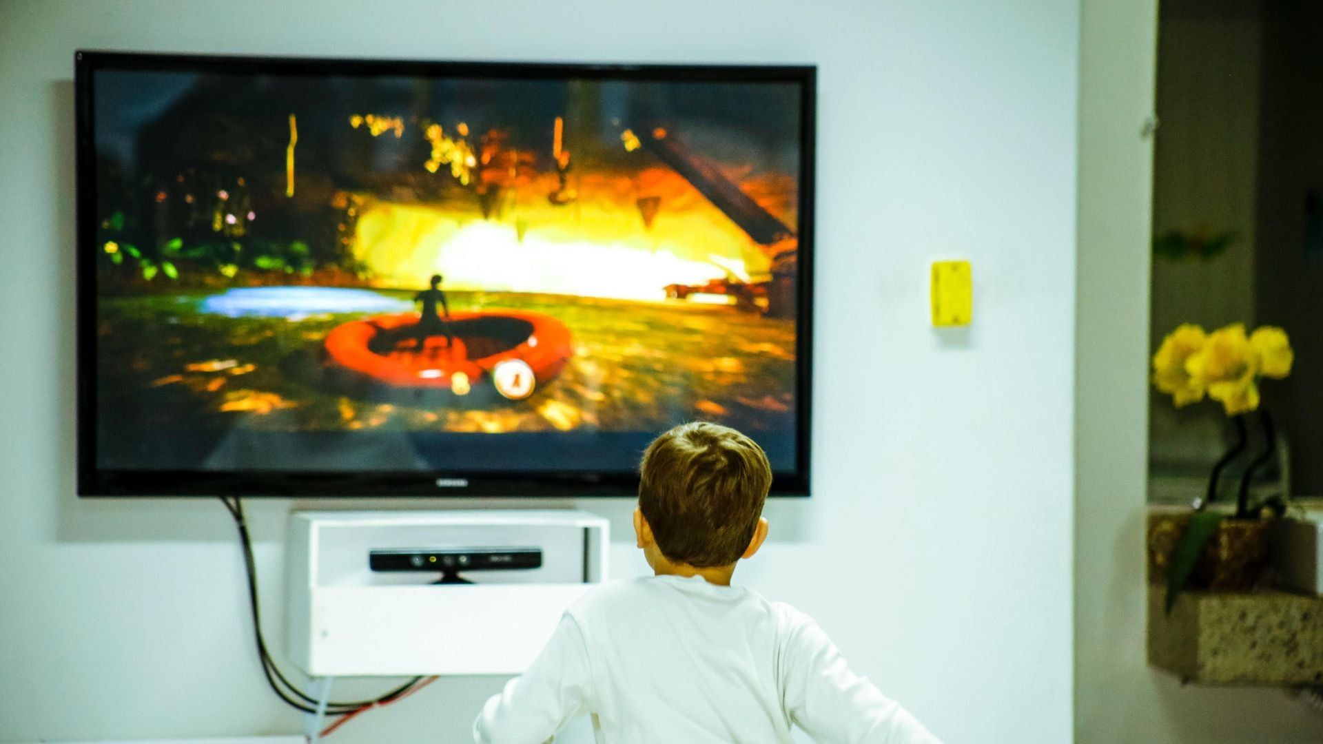Child watching video game with fiery explosion on television screen
