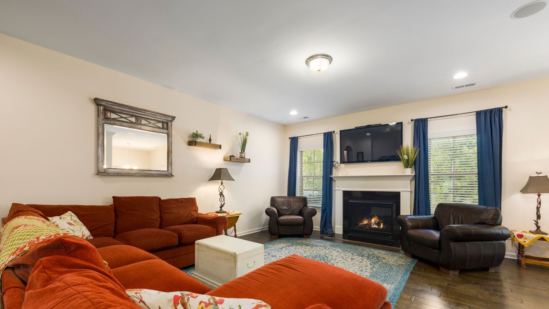 Cozy living room with fireplace, red sectional, and blue curtains