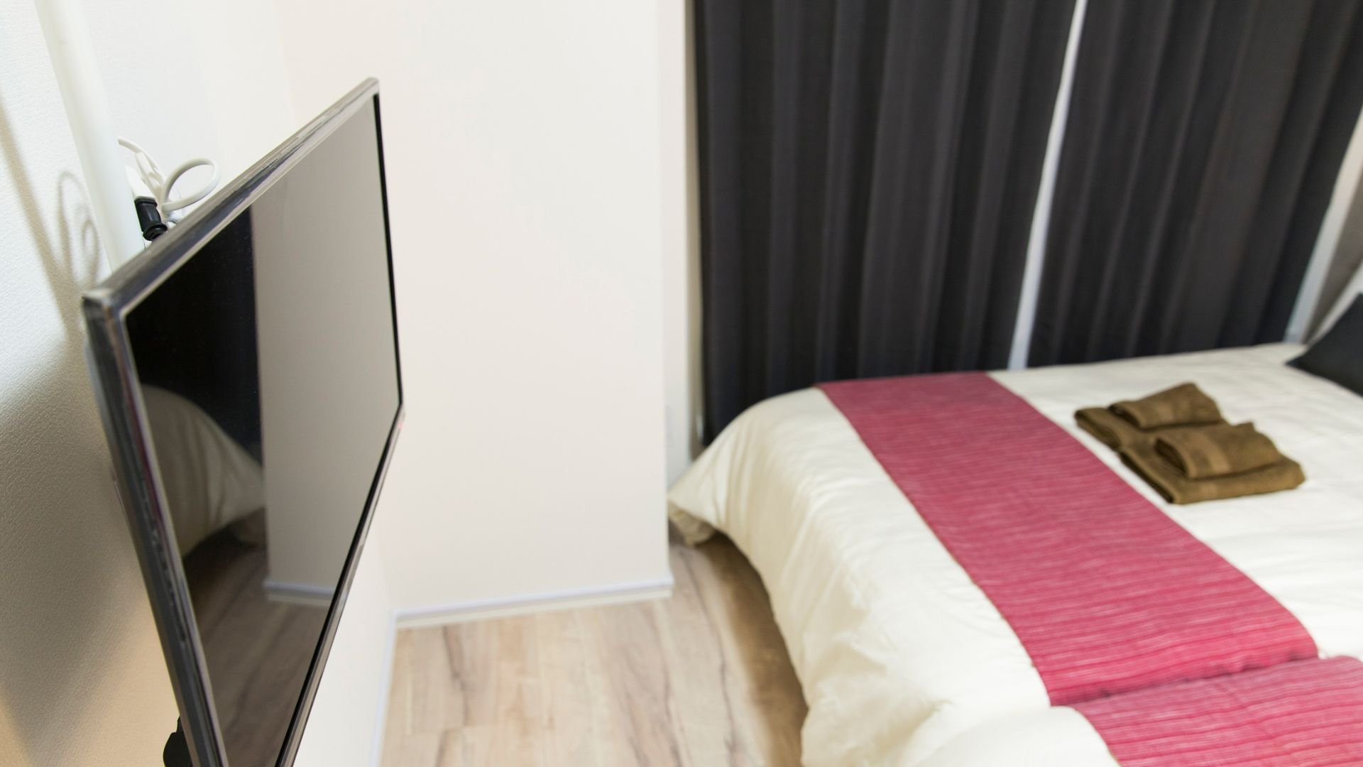 Flat screen TV mounted on wall near bed with pink and white bedding